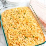 Baked cheesy onion casserole in a glass 13x9 dish with crisp buttery cracker topping and fresh parsley garnish.