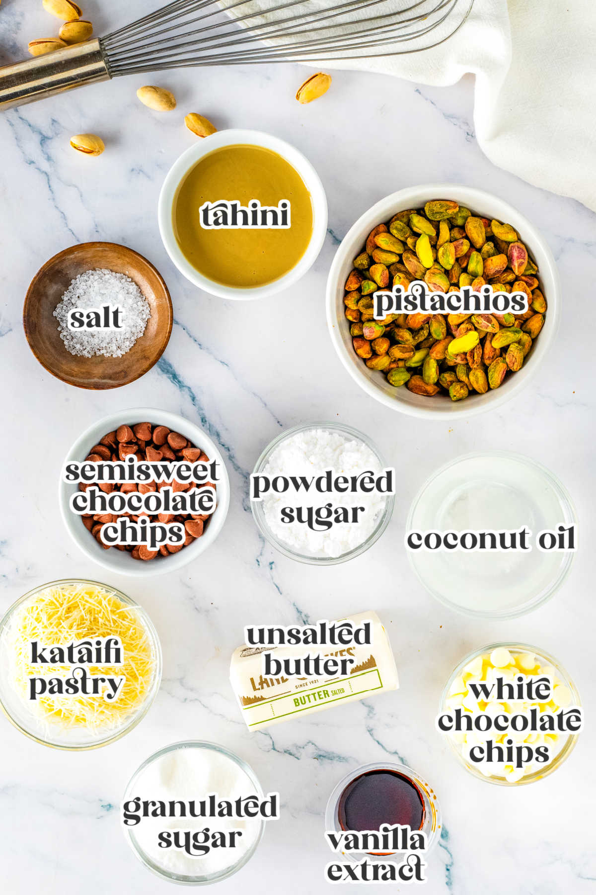 Ingredients for Dubai Chocolate Truffles laid out on a white surface, including shelled pistachios, tahini, kataifi pastry, chocolate chips, and butter.
