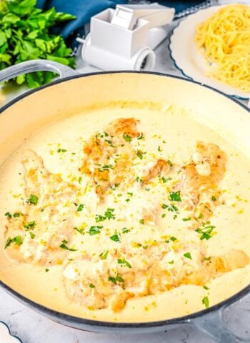 Creamy lemon chicken cooking in a skillet with parmesan cream sauce