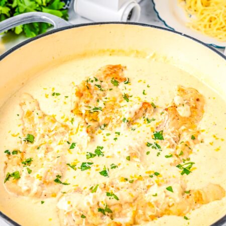 Creamy lemon chicken cooking in a skillet with parmesan cream sauce