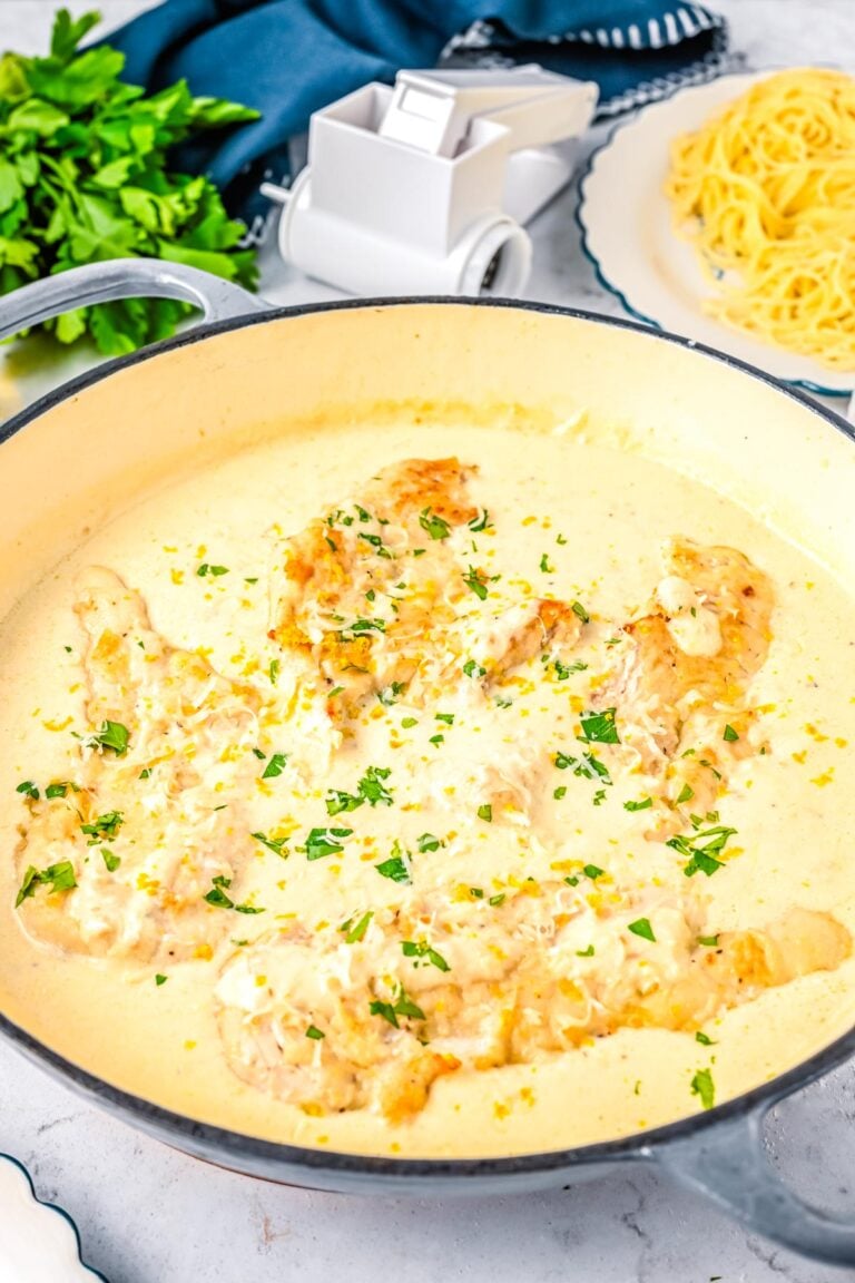 Creamy lemon chicken cooking in a skillet with parmesan cream sauce