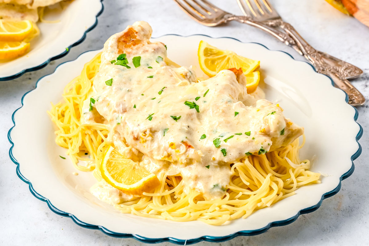 Creamy lemon chicken served over pasta with parmesan cheese and fresh parsley.