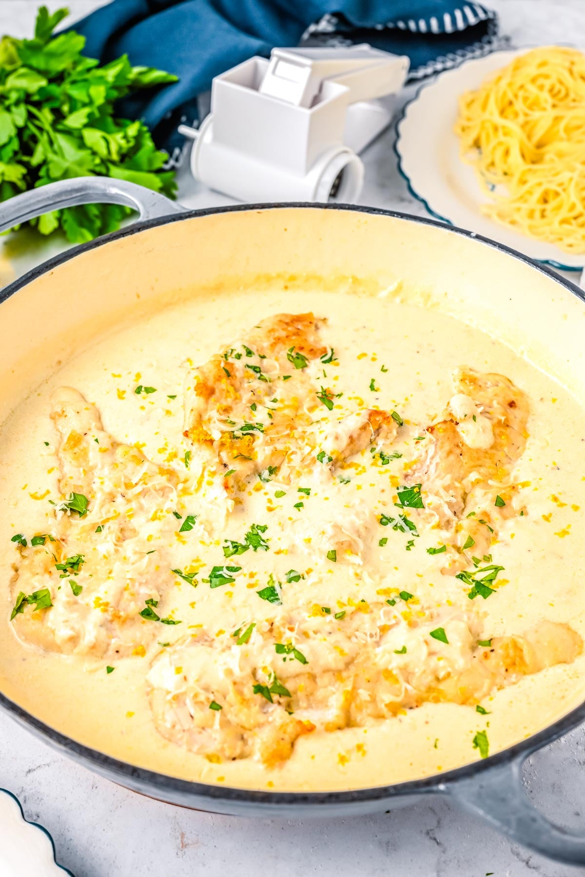 Creamy lemon chicken cooking in a skillet with parmesan cream sauce