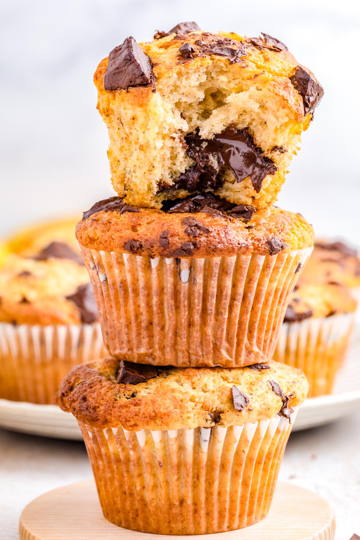 Close up of stacked chocolate chunk banana muffins showing soft crumb and melted chocolate chunks inside.