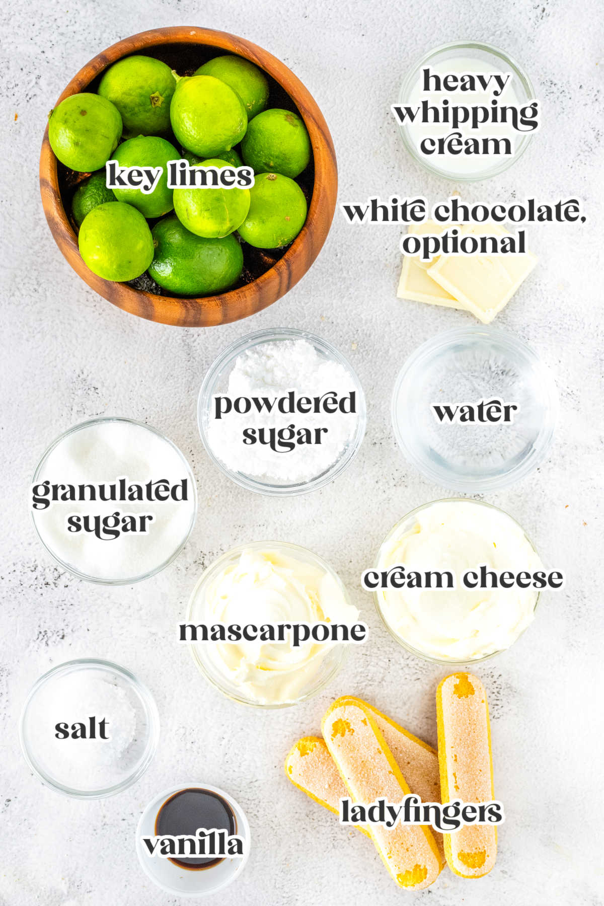 Ingredients arranged for key lime tiramisu including limes and cheeses.